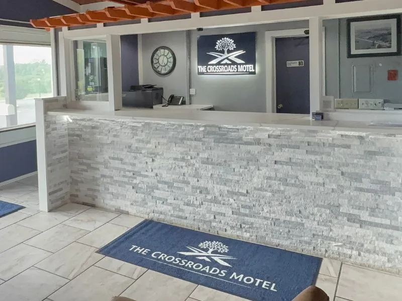 Front desk with a stone-clad counter and The Crossroads Motel sign