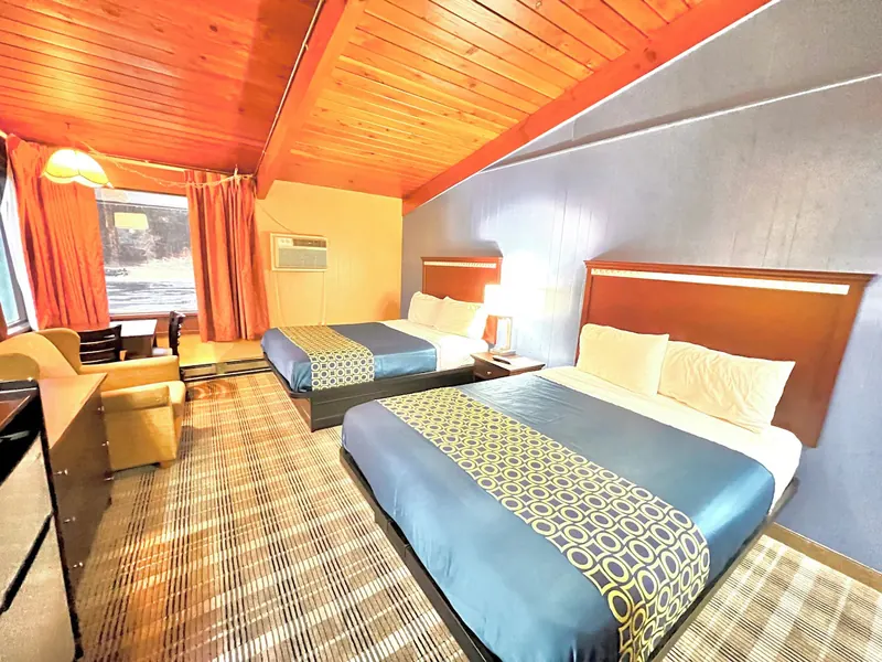 Double queen room with a pitched ceiling and bright orange curtains